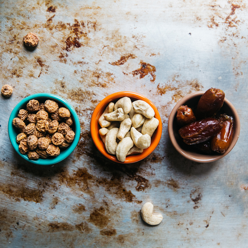 three colorful bowls with peanuts, cashew nuts, and 
